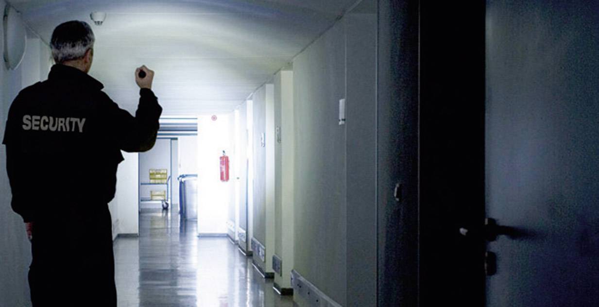Sicherheitsdienst-Mitrarbeiter mit Taschenlampe