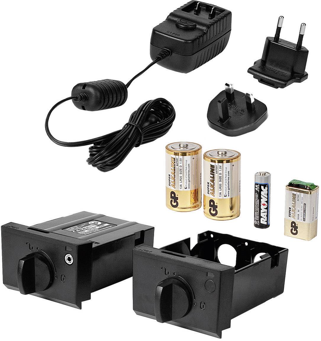 Ein Set aus Ladegerät mit verschiedenen Steckdosenadaptern, zwei großen Batterien, einer kleinen Batterie und zwei schwarzen Halterungen für Batterien.