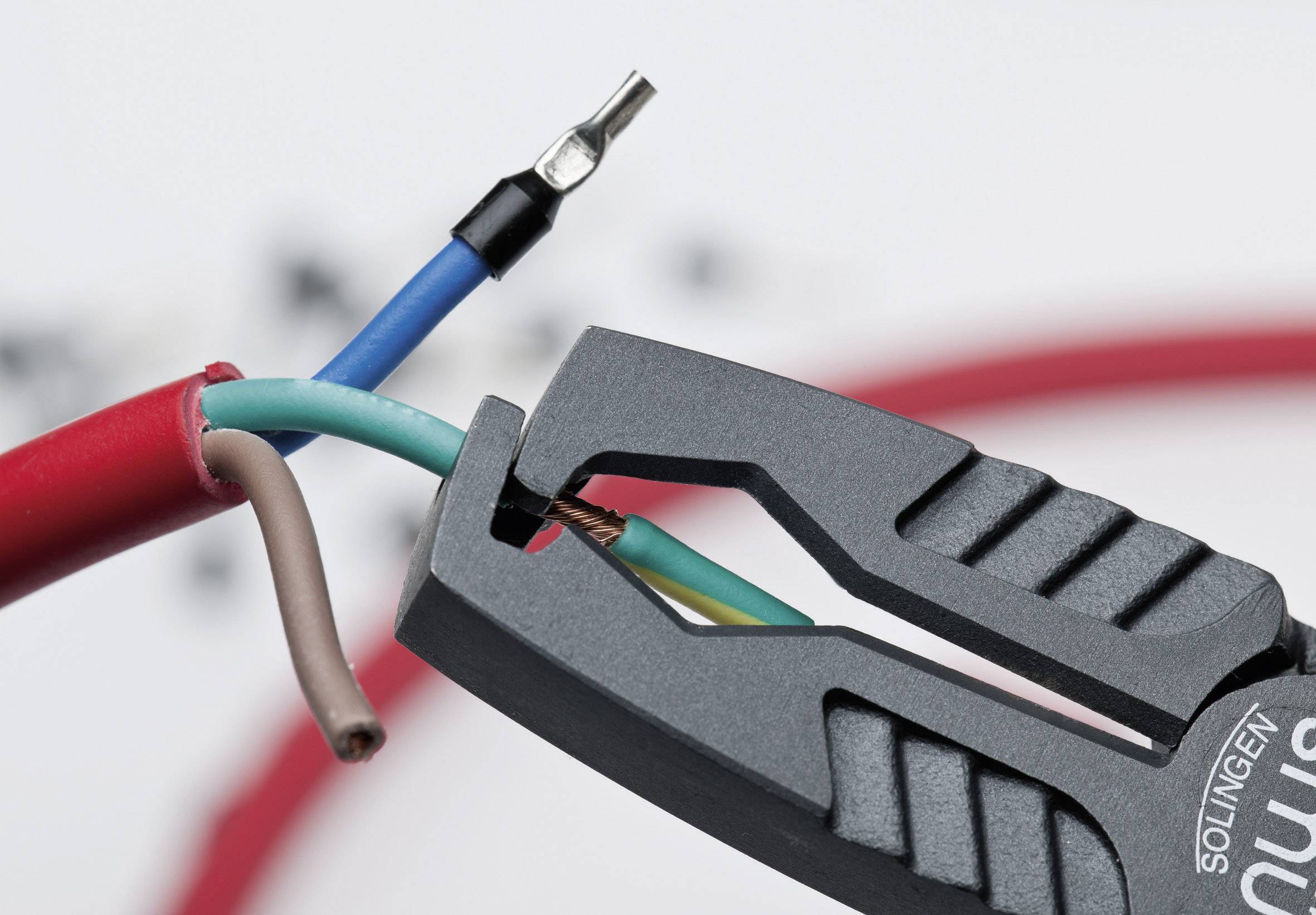 'Nahaufnahme eines Kabelschneiders, der ein elektrisches Kabel mit mehreren farbigen Adern schneidet.'