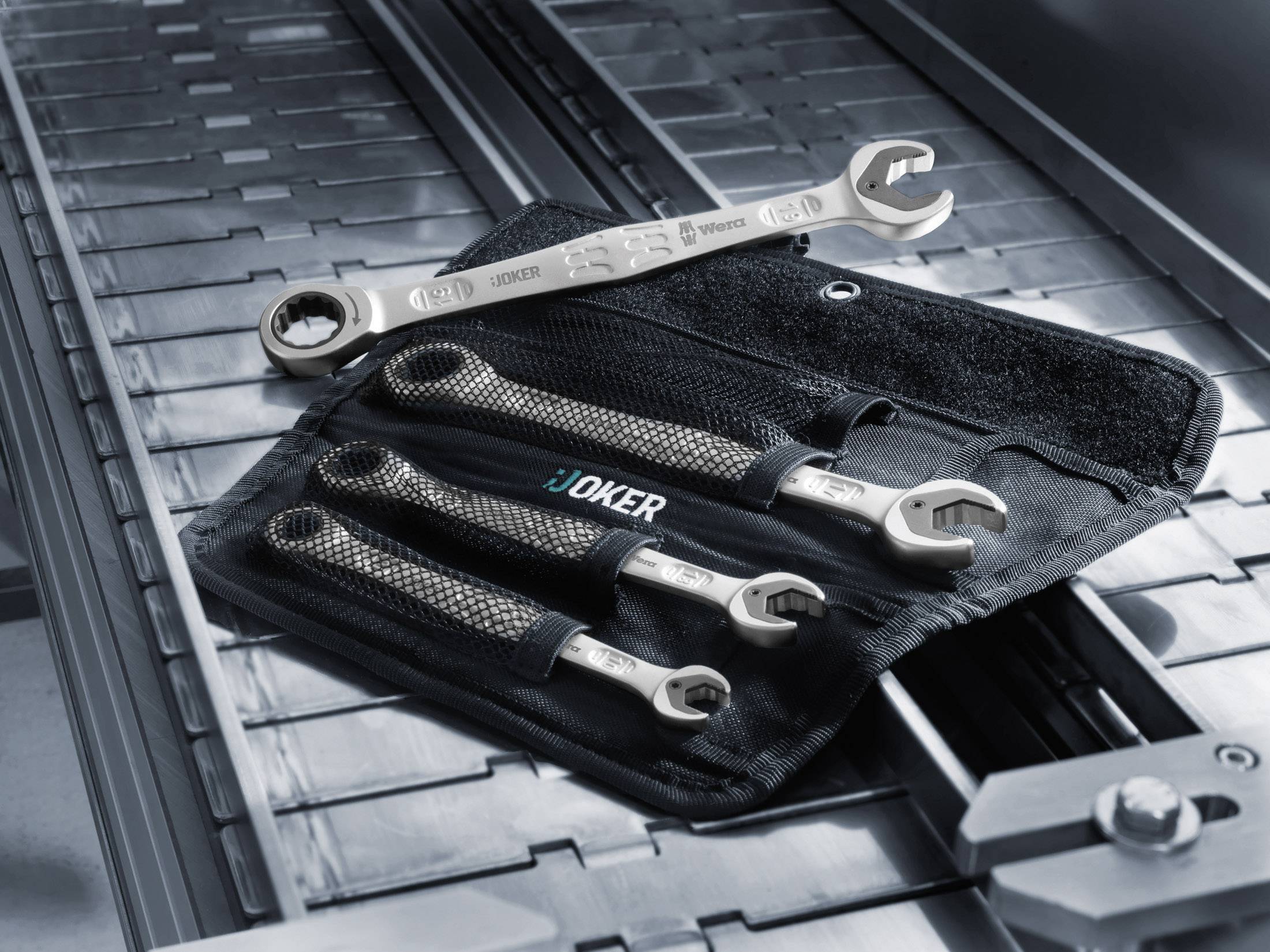 Vier Joker-Ringschlüssel in verschiedenen Größen liegen auf einer Werkzeugtasche auf einem metallischen Untergrund.