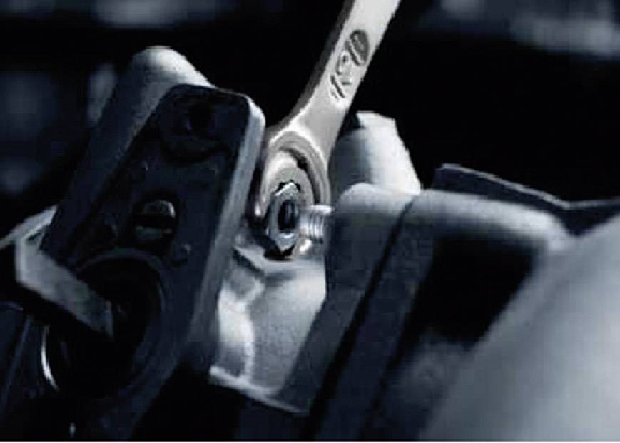 Ein Schraubenschlüssel zieht eine Schraube an einem mechanischen Teil fest. Die Szene zeigt Nahaufnahme von Handwerkzeugen bei der Arbeit.