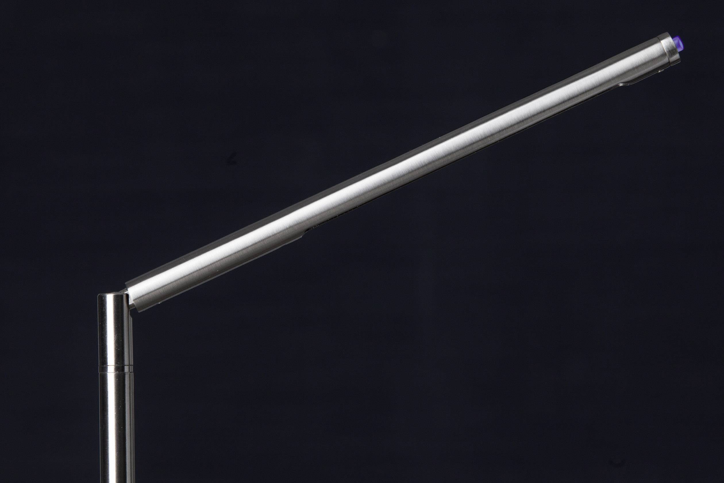 Eine elegante, schlanke Schreibtischlampe mit modernem Design vor einem dunklen Hintergrund.