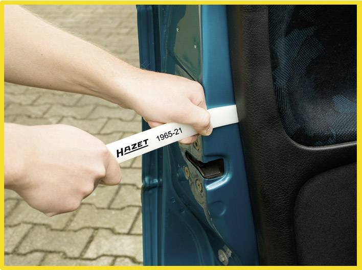 'Person hält ein weißes Werkzeug der Marke Hazet, Modellnummer 1965-21, zwischen Autotür und Rahmen.'