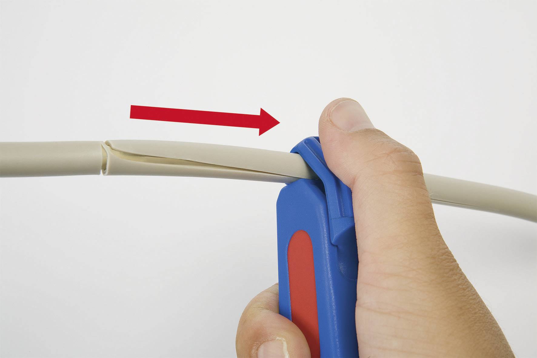 Ein Hand hält ein Kabel, das mit einem blauen Werkzeug geschnitten wird. Ein roter Pfeil zeigt die Schneidrichtung an.