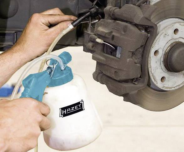 'Ein Mechaniker entlüftet die Bremsen eines Fahrzeugs mit einem Bremsenentlüftungsgerät.'