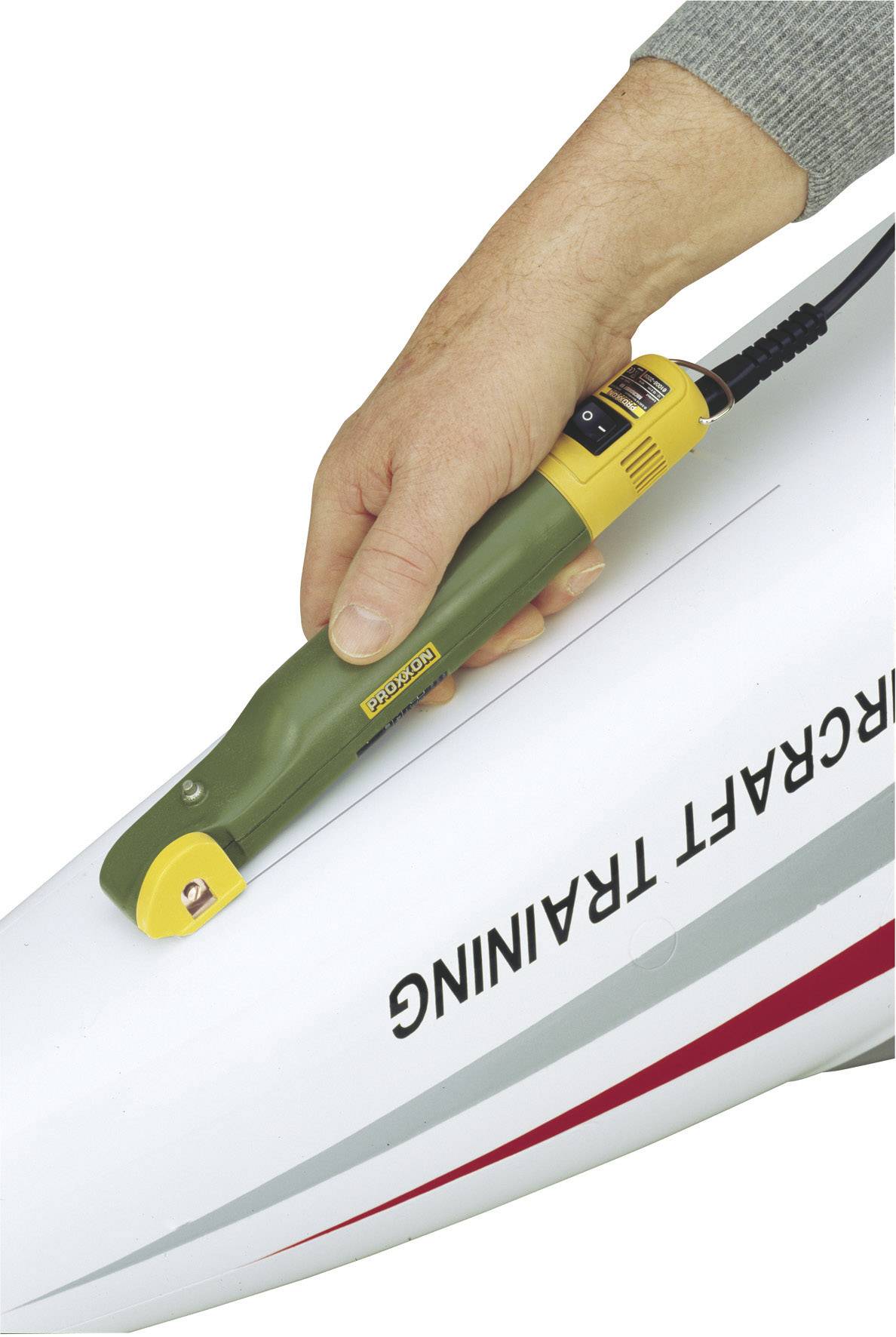 Hand hält ein Modellbauwerkzeug auf dem Flugzeugrumpf mit der Aufschrift 'Aircraft Training'.