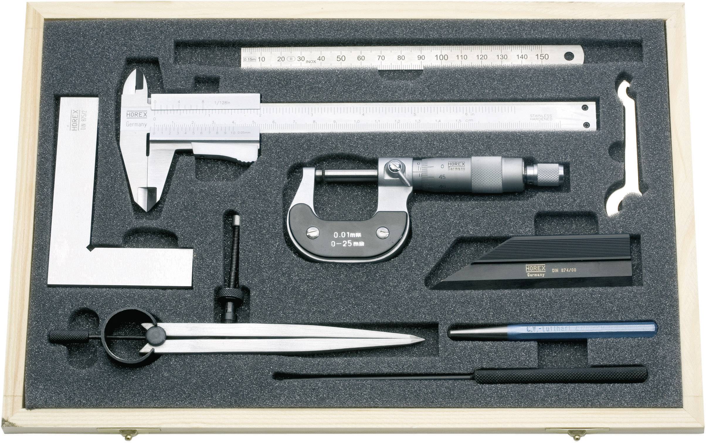 as Bild zeigt eine Holzkiste, die verschiedene Präzisionsmesswerkzeuge enthält, eingebettet in eine passende Schaumstoffeinlage.  Die Werkzeuge umfassen einen Messschieber, ein Mikrometer, ein Lineal, ein Winkelmaß, einen Zirkel, einen kleinen Schraubenschlüssel, einen Winkelmesser, eine Anreißnadel und einen Entgrater.