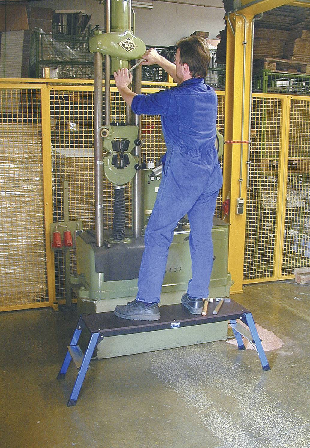 'Mann in Arbeitskleidung bedient eine industrielle Maschine in einer Werkstatt.'