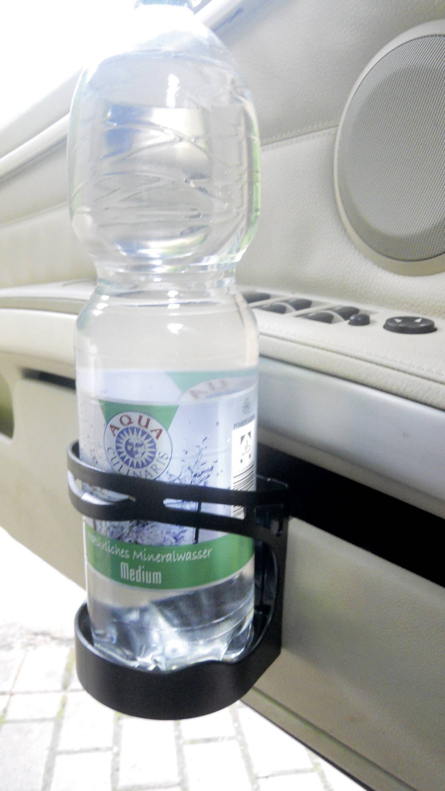 Eine Plastik-Wasserflasche steht in einem Flaschenhalter, der an der Innenseite einer Autotür befestigt ist. Im Hintergrund sind Autoinnendetails sichtbar.