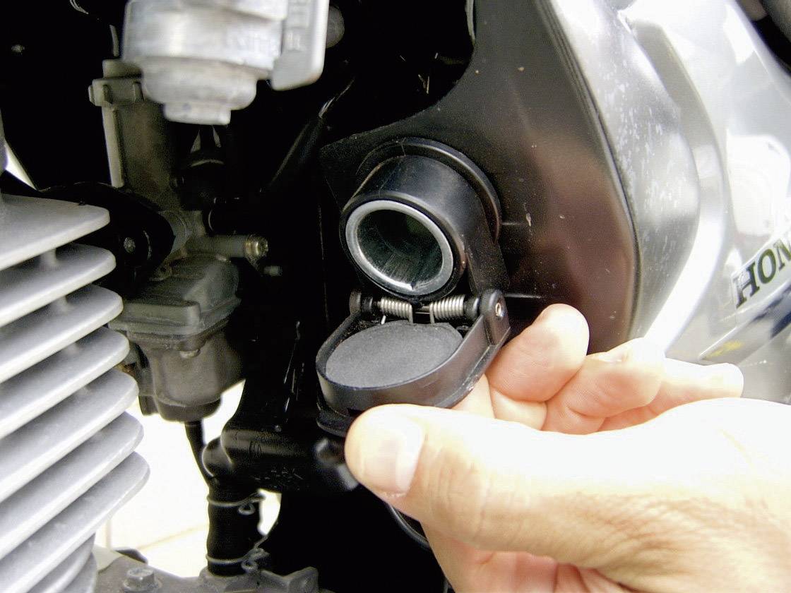 'Hand öffnet Motorabdeckung, zeigt Maschinenkomponente.'