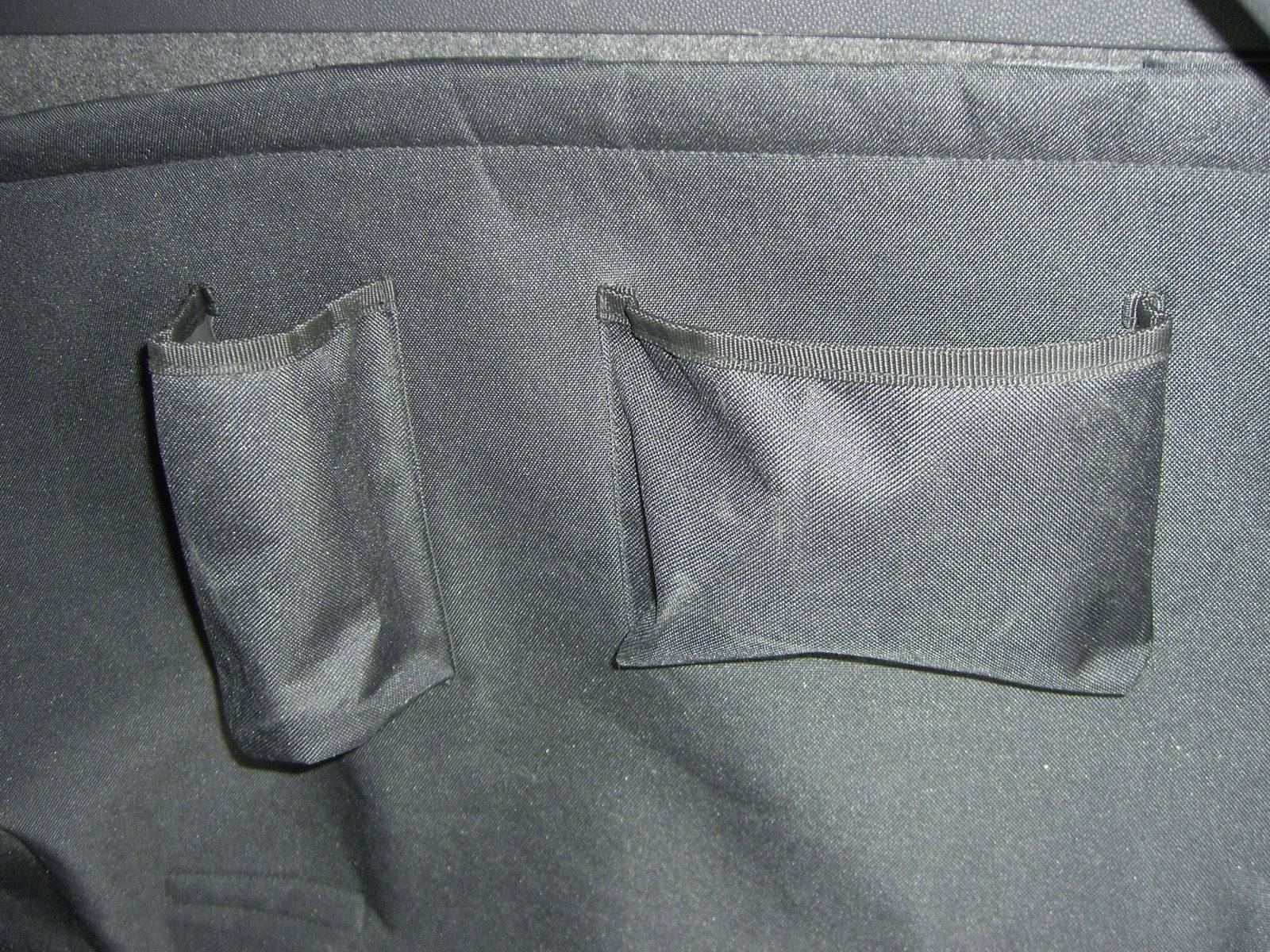 Zwei schwarze Stofffächer auf einer schwarzen Oberfläche, vermutlich Teil einer Tasche oder eines Kleidungsstücks.