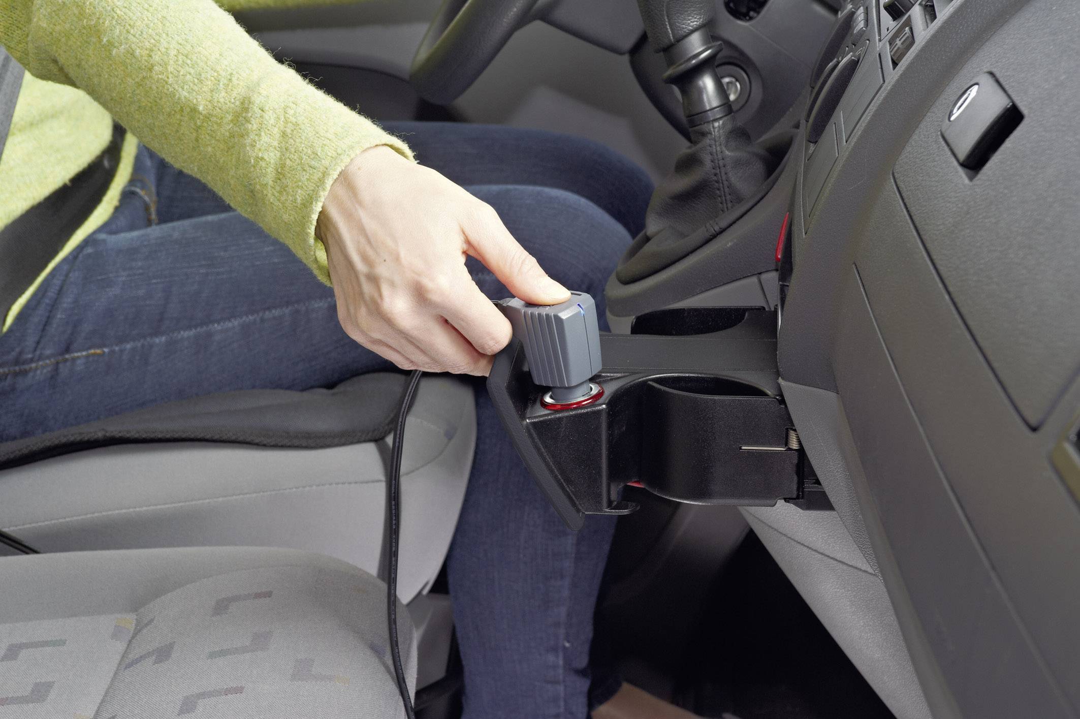 Eine Person dreht den Drehknopf einer Handbremse im Auto. Die Handbremse scheint als eine zusätzliche, manuelle Kontrolle installiert zu sein.