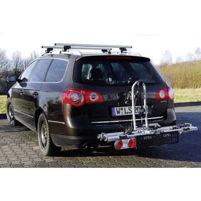 Ein dunkelbrauner Kombi mit einem Fahrradträger auf der Anhängerkupplung steht auf einem gepflasterten Parkplatz vor einem bewaldeten Hintergrund.