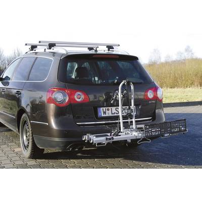 Auto mit abnehmbarem Fahrradträger am Heck, geparkt auf gepflastertem Platz. Träger ist leer, klarer Himmel und Bäume im Hintergrund.