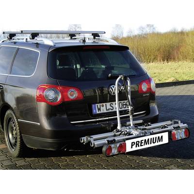 Ein Auto mit montiertem Fahrradträger am Heck, steht auf einem Parkplatz, umgeben von Wiese und Bäumen im Hintergrund.