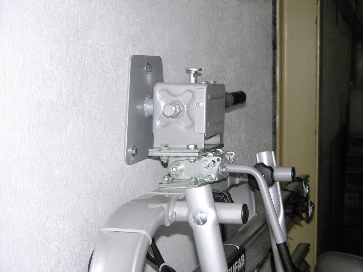 Ein Metallschloss mit Kette sichert ein zusammengeklapptes Gartengerät an einer Wandhalterung.