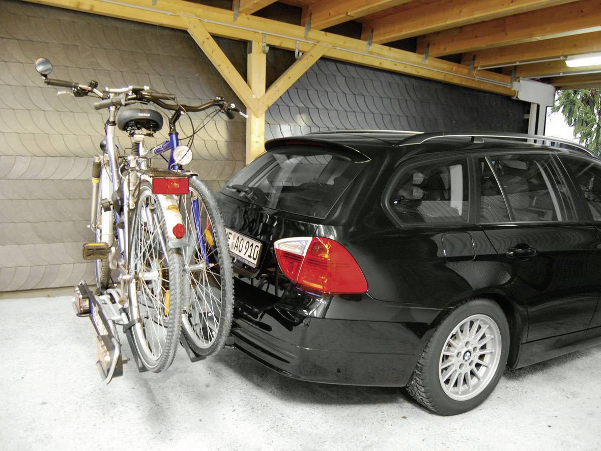 Auto mit Fahrradträger, der zwei Fahrräder trägt, geparkt in einer überdachten Garage.