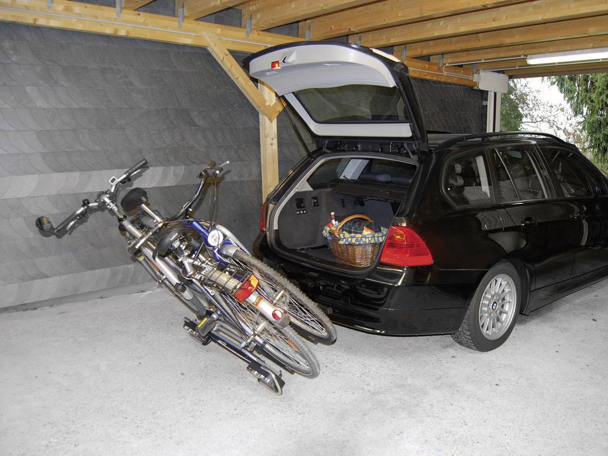 Schwarzer Kombi in einer Garage mit offenem Kofferraum; darin ein umgefallenes Fahrrad und ein Korb.