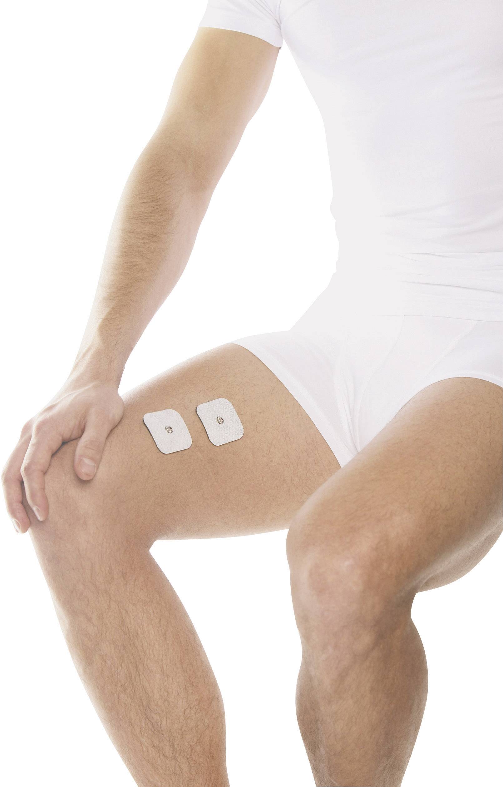 Ein Mann in weißer Kleidung sitzt, zeigt zwei rechteckige Elektroden auf dem rechten Oberschenkel.