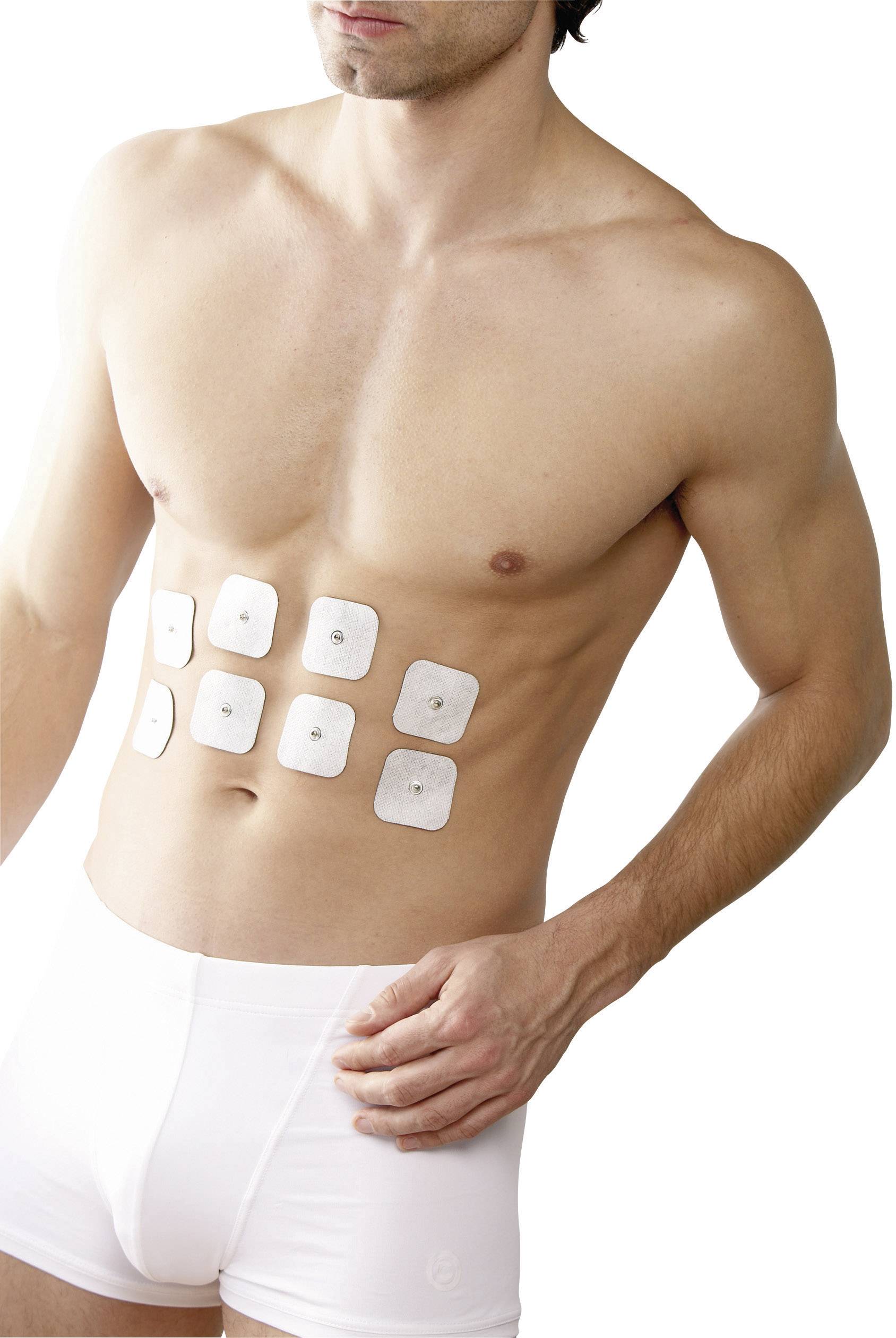 Ein Mann steht in Unterwäsche, mit mehreren Pflastern oder Elektroden auf seinem Bauch befestigt.