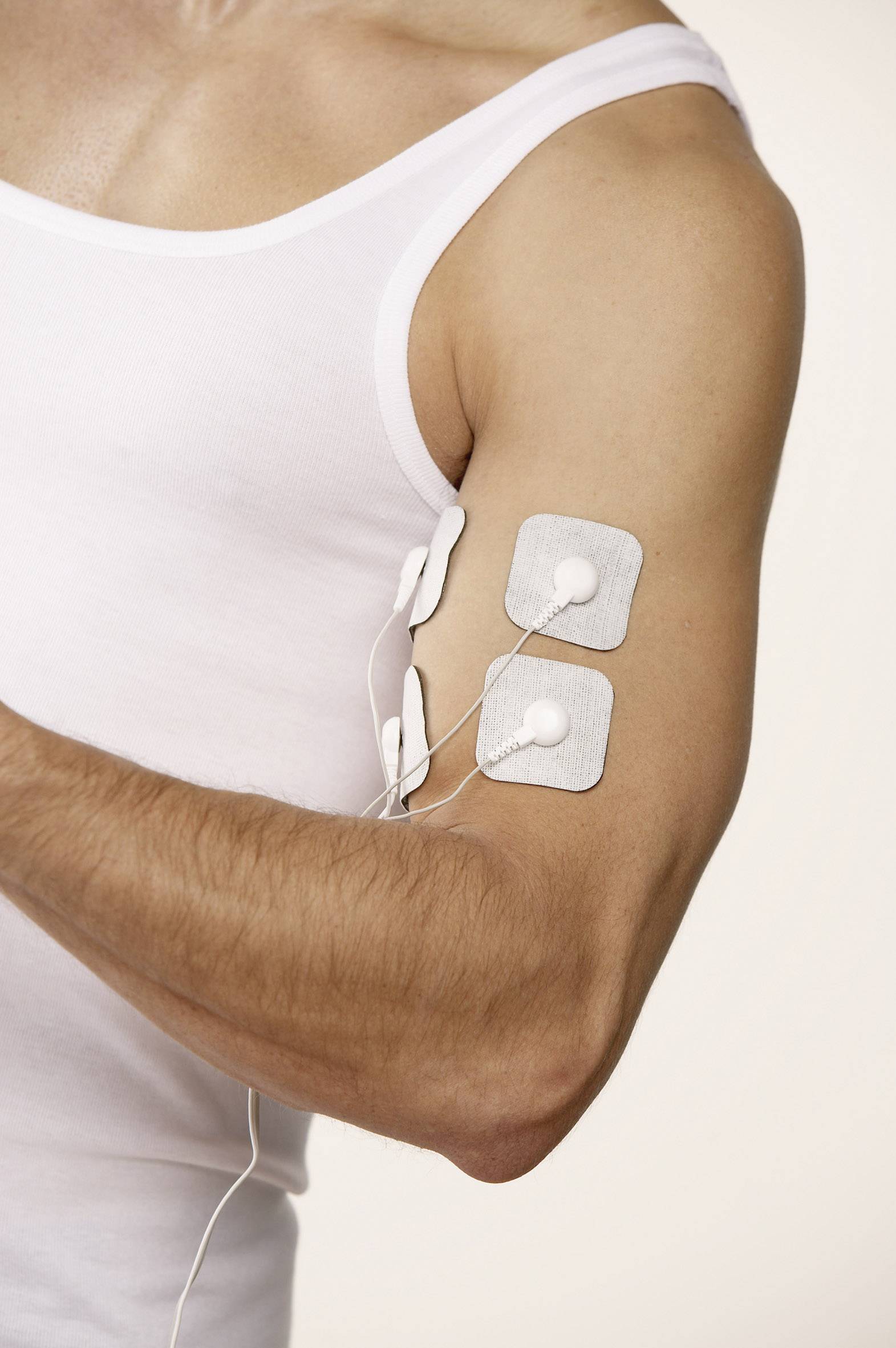 Ein Mann in einem weißen Tanktop hat Elektroden auf seinem Oberarm angebracht.