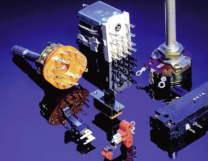 Verschiedene elektronische Bauteile wie Dreh- und Schiebepotentiometer liegen auf einer glänzenden Oberfläche.