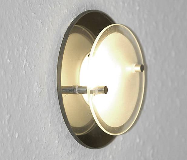 Wandleuchte an einer hellen Wand mit rundem, modernem Design. Die Lampe leuchtet warmes, diffuses Licht.