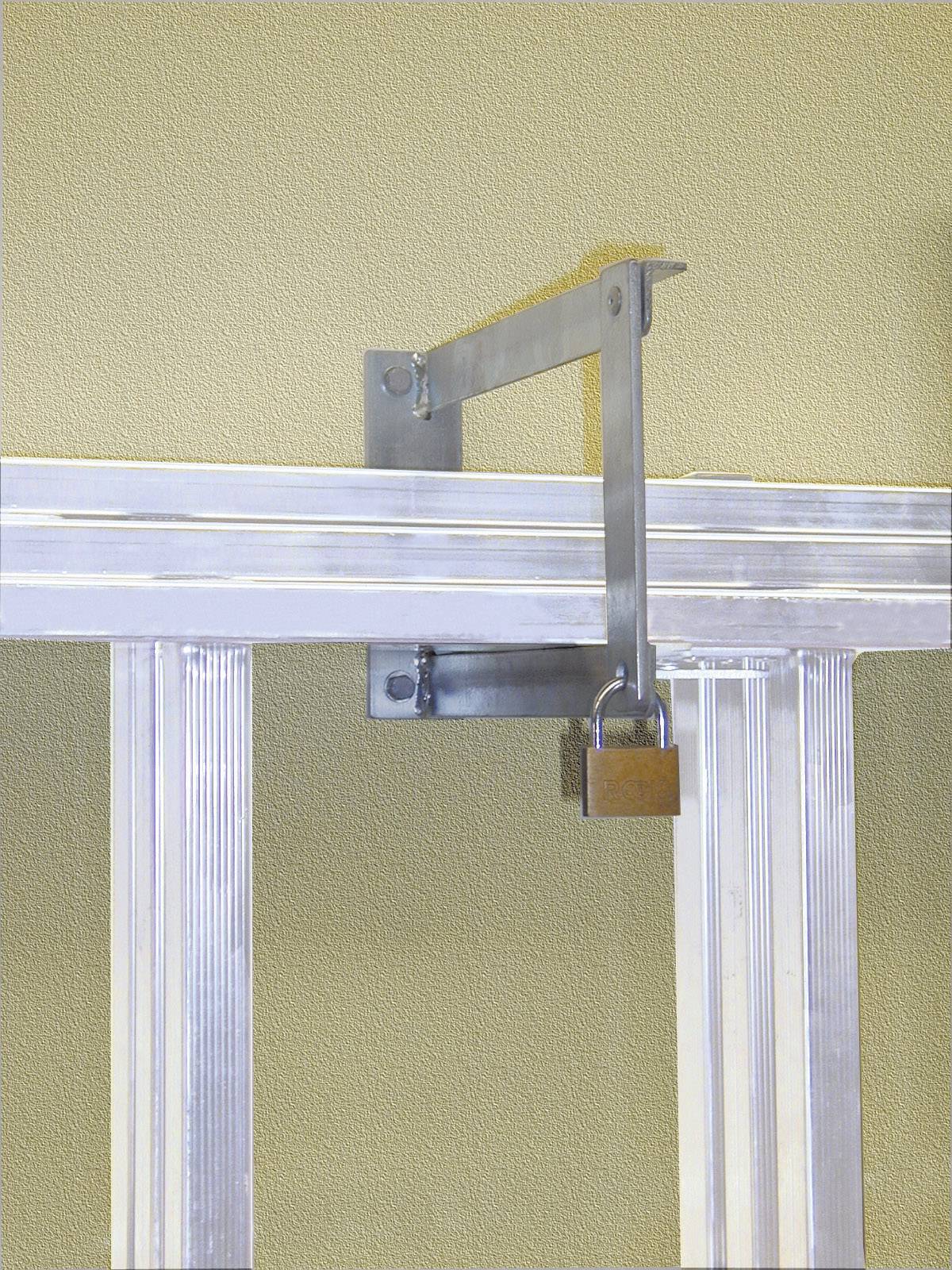 Ein Metallriegel mit Vorhängeschloss sichert ein Schiebetor. Der Riegel ist an der Oberkante des Tores befestigt.