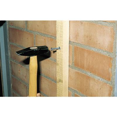 Ein Hammer treibt einen Nagel in ein Holzbrett, das an einer Ziegelwand befestigt ist.