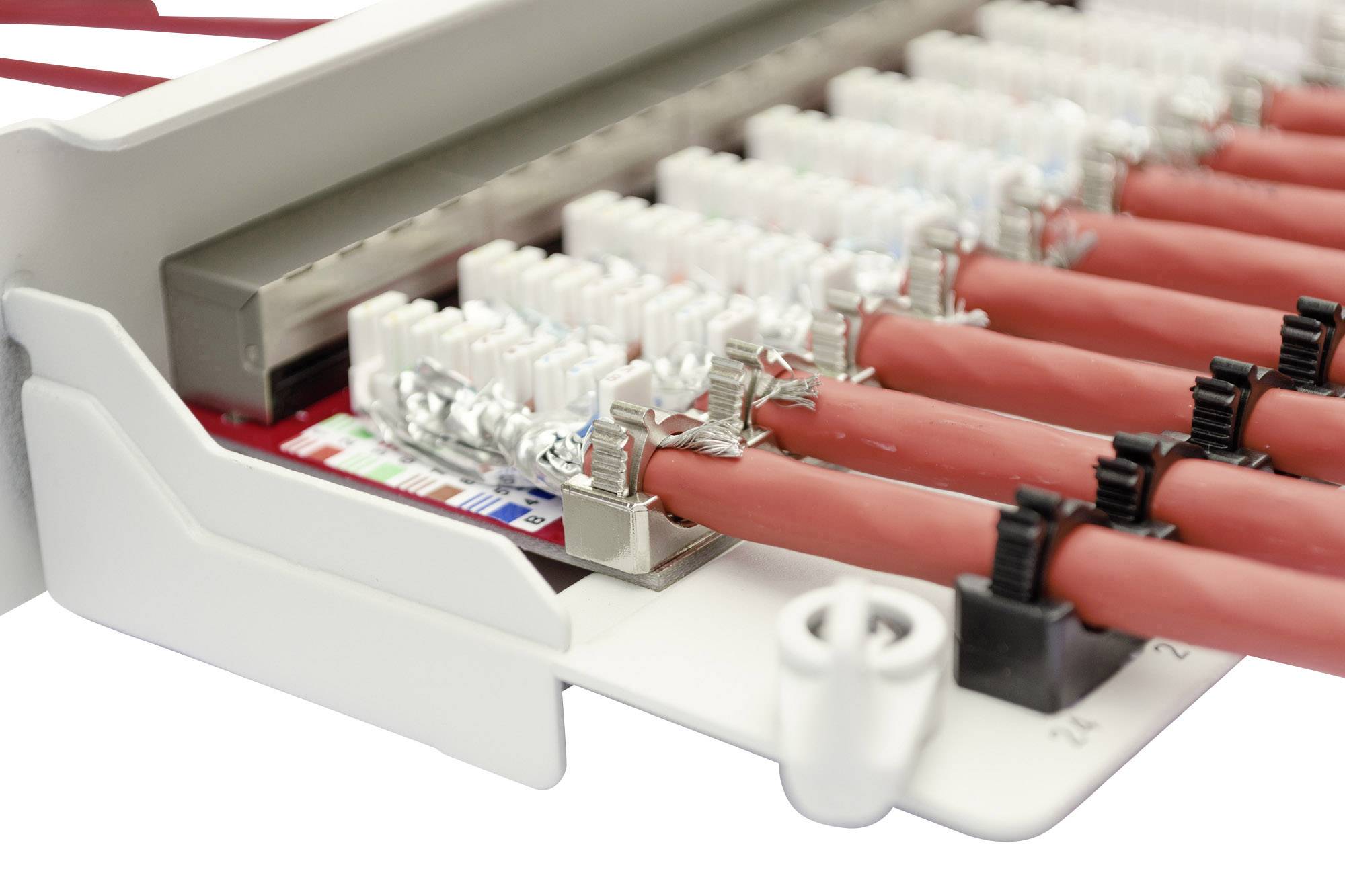 Rote Netzwerk- oder Telefonkabel sind in einer Verteilerleiste eingesteckt. Die Nahaufnahme zeigt detaillierte Anschlüsse und Drähte.