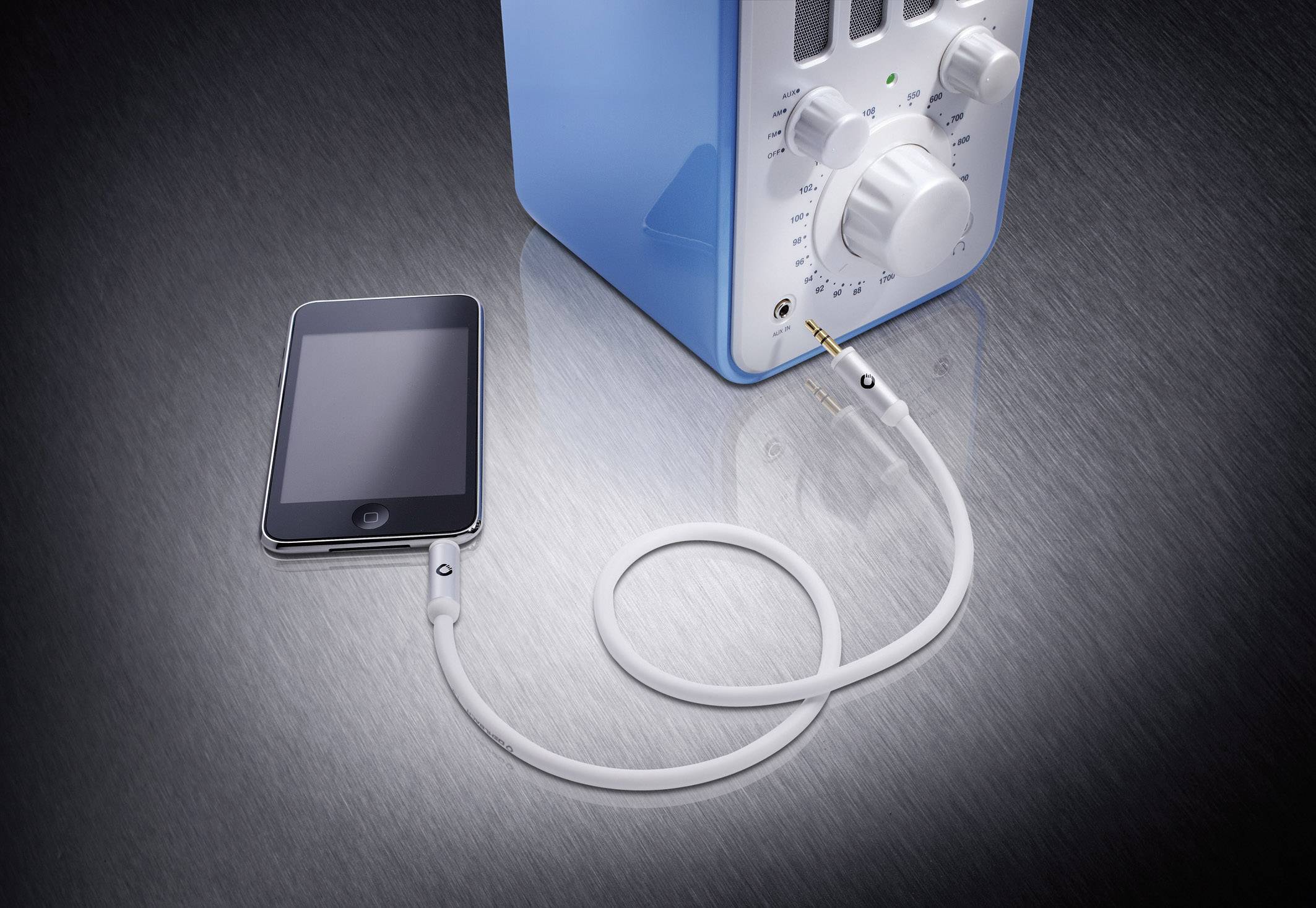 Ein Smartphone ist mit einem blauen Radio über ein weißes Audiokabel verbunden.