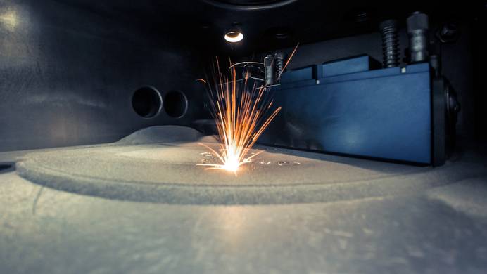 Selektives Lasersintern mithilfe eines Hochenergielasers Auf dem Bild sieht man einen Industrie-Drucker beim Lasersintern. Der dabei entstehende Funkenflug veranschaulicht die hohe Energie des Lasers.