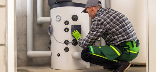 Warungsarbeiten an einem Warmwasserboiler Das Bild zeigt einen Monteur, der Wartungsarbeiten an einem Warmwasserboiler durchführt.