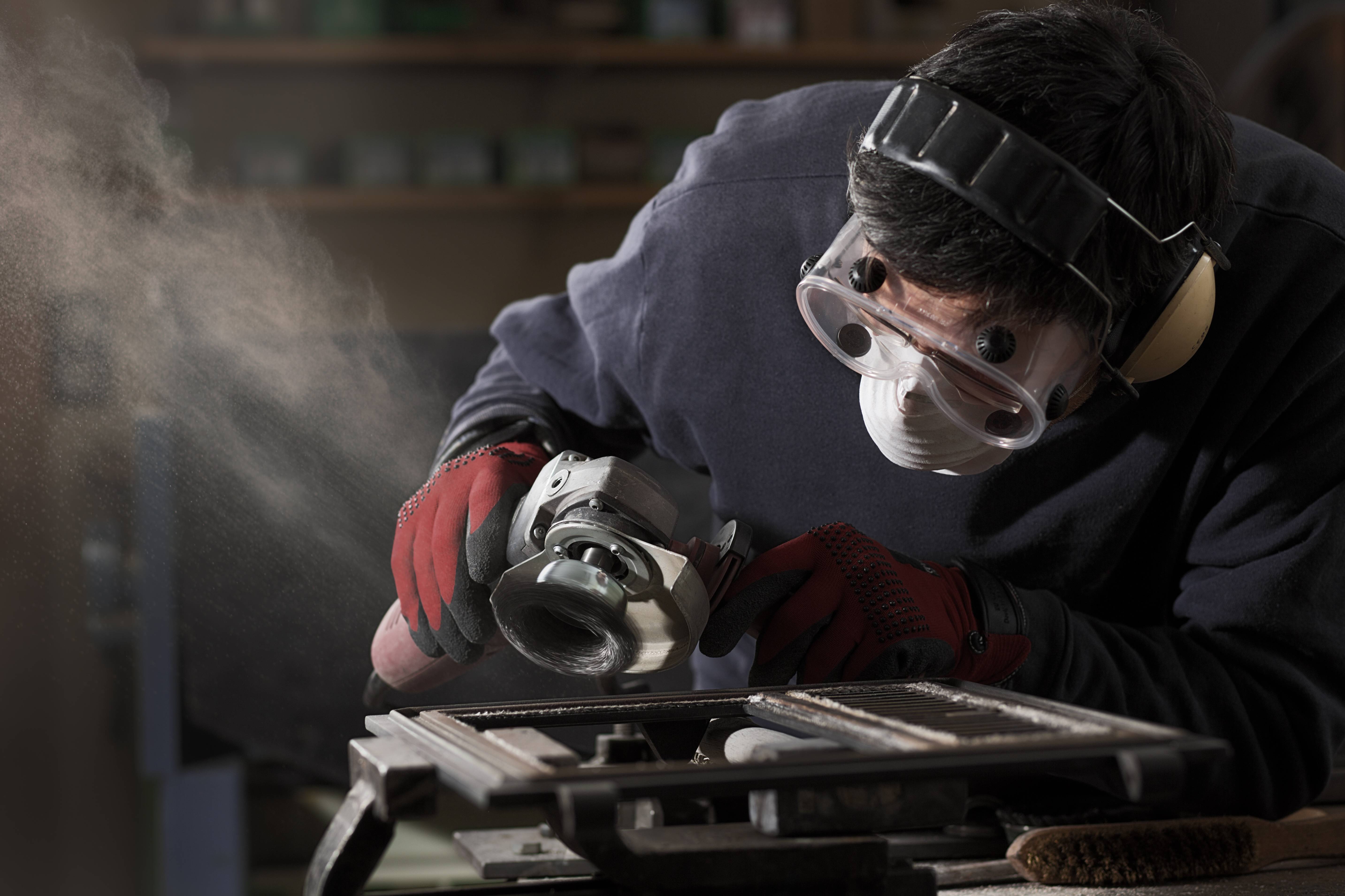 Auf dem Bild ist ein Handwerker mit einer Feinstaubmaske zu erkennen.