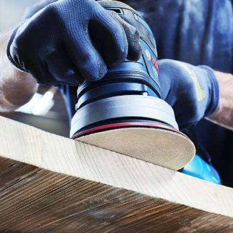 Person bearbeitet Holz mit einem Bosch Exzenterschleifer.