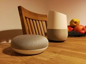 Zwei verschiedene Google Home Sprachassistenten auf einem Holztisch, als Bestandteil eines Smart Home.