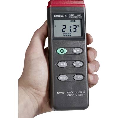 A hand is holding an electronic thermometer by Voltcraft. The display shows 21.3°C. Buttons are present for Hold, Timer, Average, Max, Min and unit change.