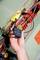 A hand holds an electrical testing device with cables in an electrical cabinet. Colourful wires and labels are visible.