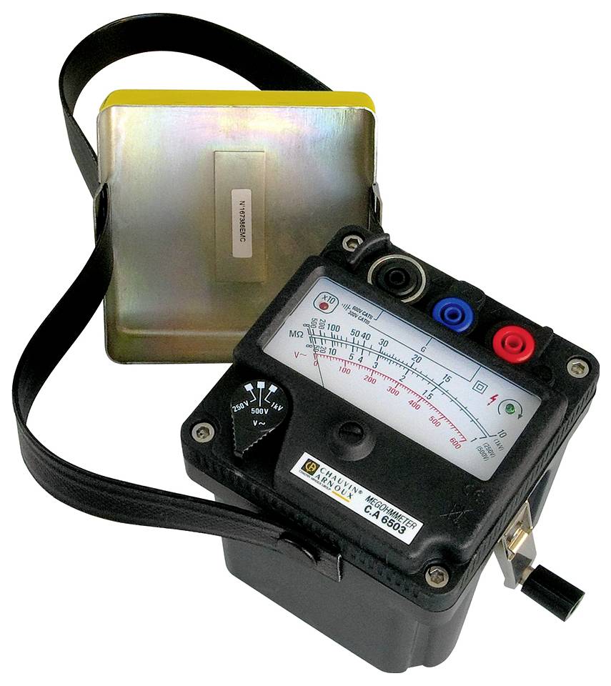 Analogue measuring device with a pointer and cables, showing electrical measurements. Metallic back panel in the background, black carrying strap.