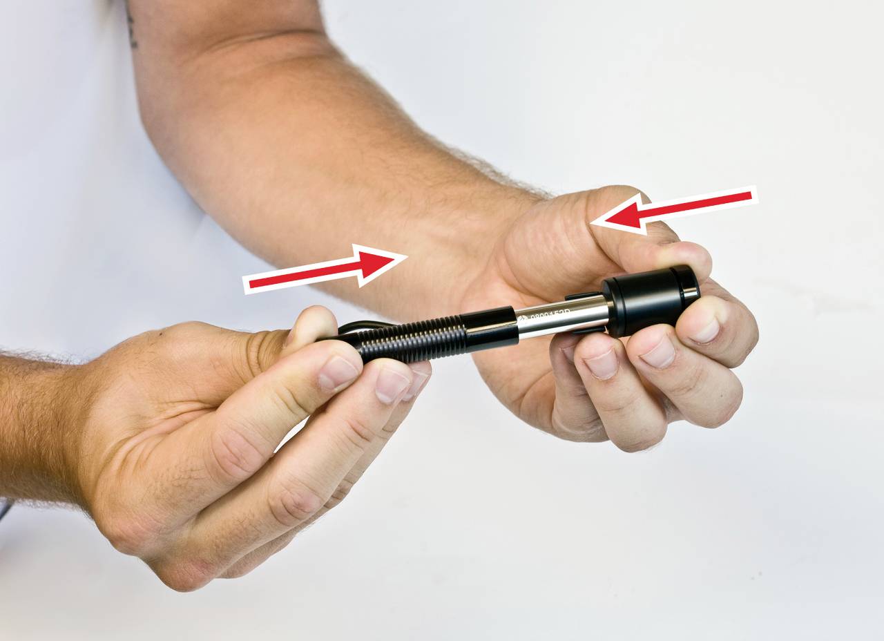 A person is holding a handy device with two hands, with arrows pointing to the junction of the parts, possibly for assembly or disassembly.