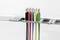 Colourful crocodile clips in blue, red, black, yellow and green hang on a metal frame at regular intervals.