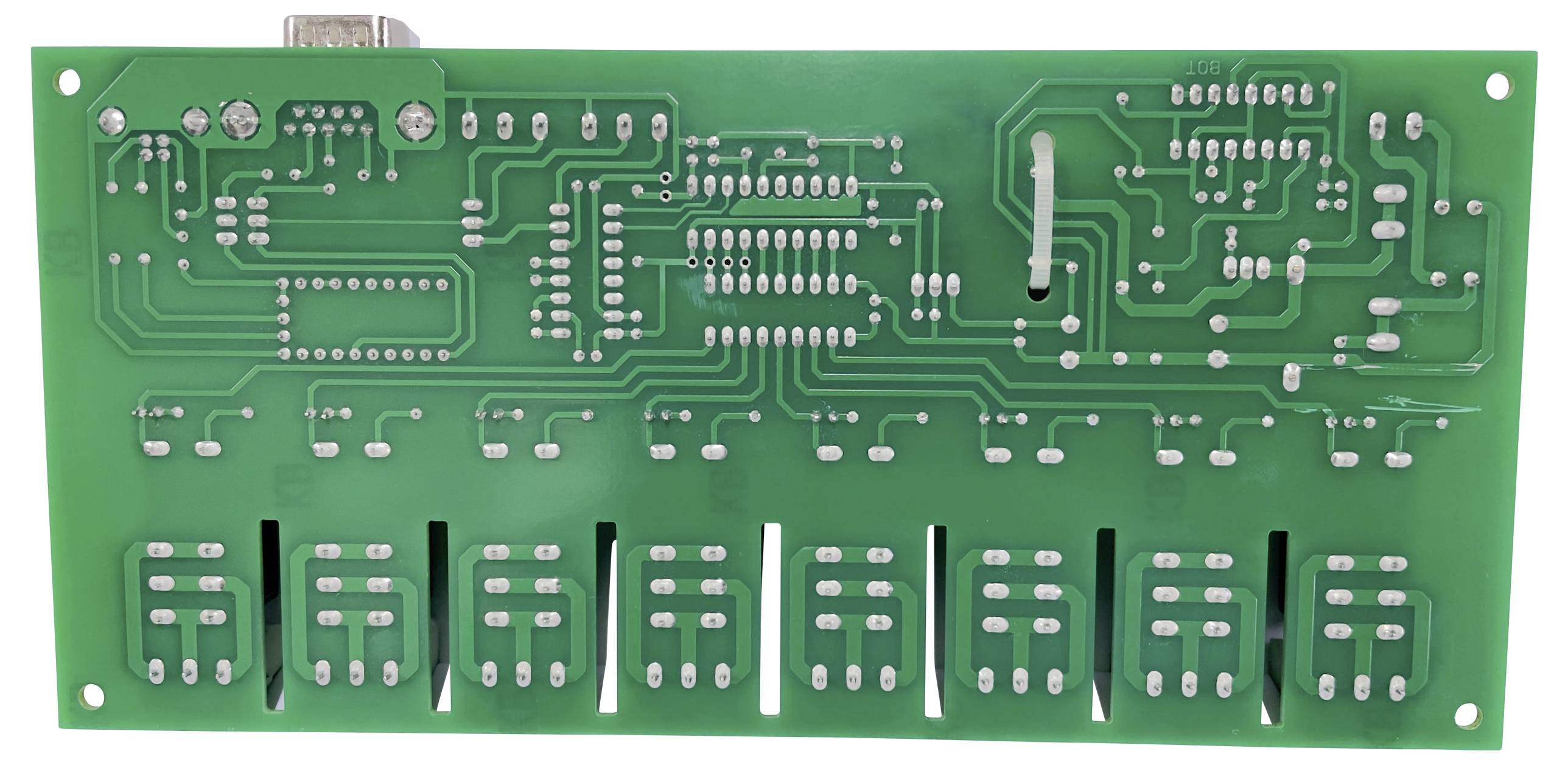 A green printed circuit board shows its reverse side with numerous circuit traces and solder points, typical components are absent.