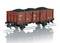 A red model railway freight wagon loaded with coal on reflective tracks, showcasing side details and logos.