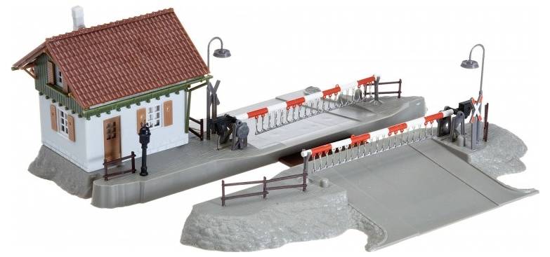 Model train crossing with a guard house, two red-and-white barriers, and two black toy figures, set on a grey base with street lamps.