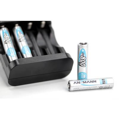 A battery charger is partially filled with blue-and-white AA batteries; another battery lies in front of it.