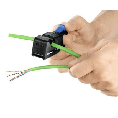 Hands are holding a wire stripping tool that is stripping a green cable. The inner wires of the cable are visible.