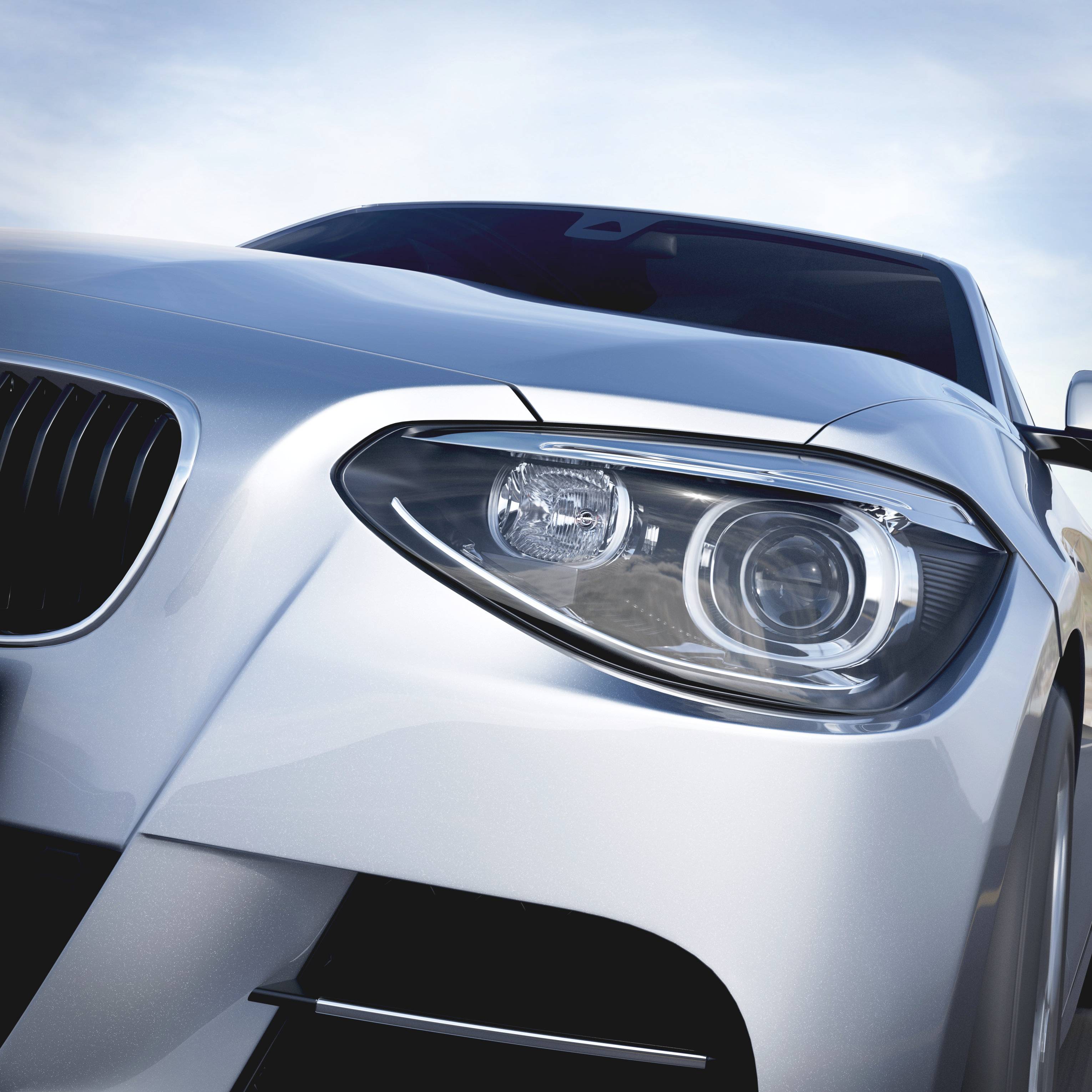 Front view of a gleaming silver car with a modern headlight design, against a blue sky.