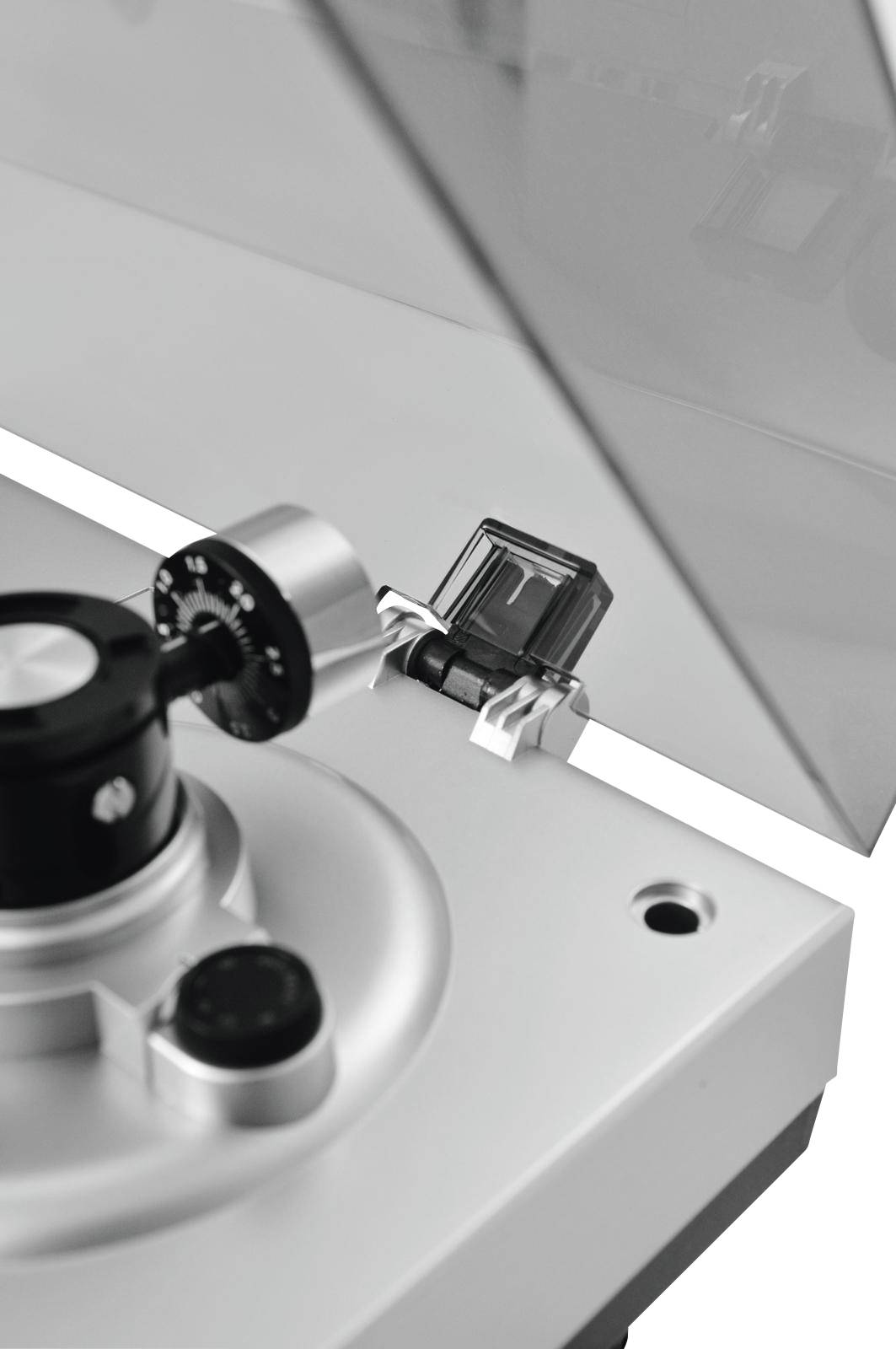 A silver device with a scale and needle, possibly a record player or measuring instrument, beneath a transparent lid.