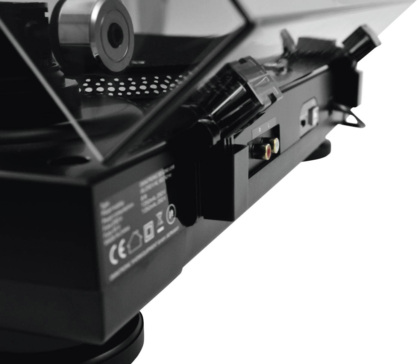 Close-up of a record player with a closed acrylic lid. The tonearm and various connections on the side are visible.