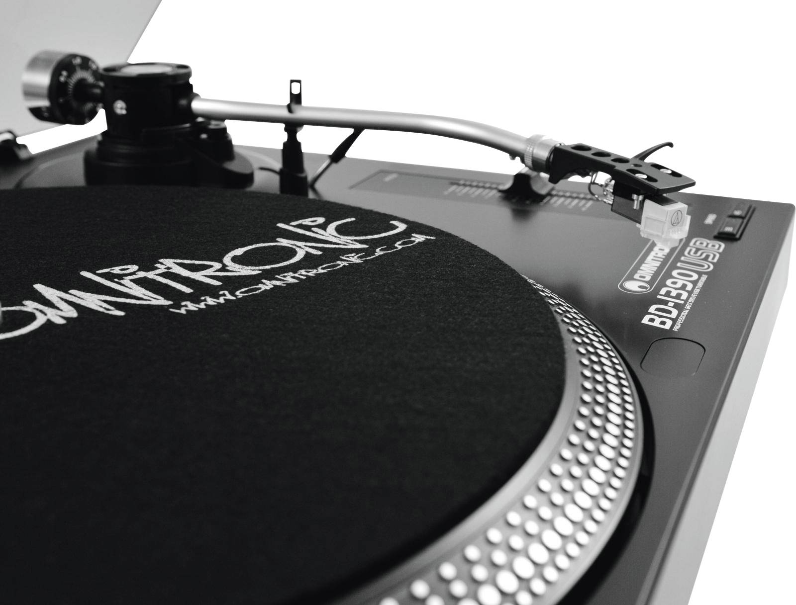 A record player with a tonearm and stylus on a black vinyl record. A logo on the mat is partially visible.